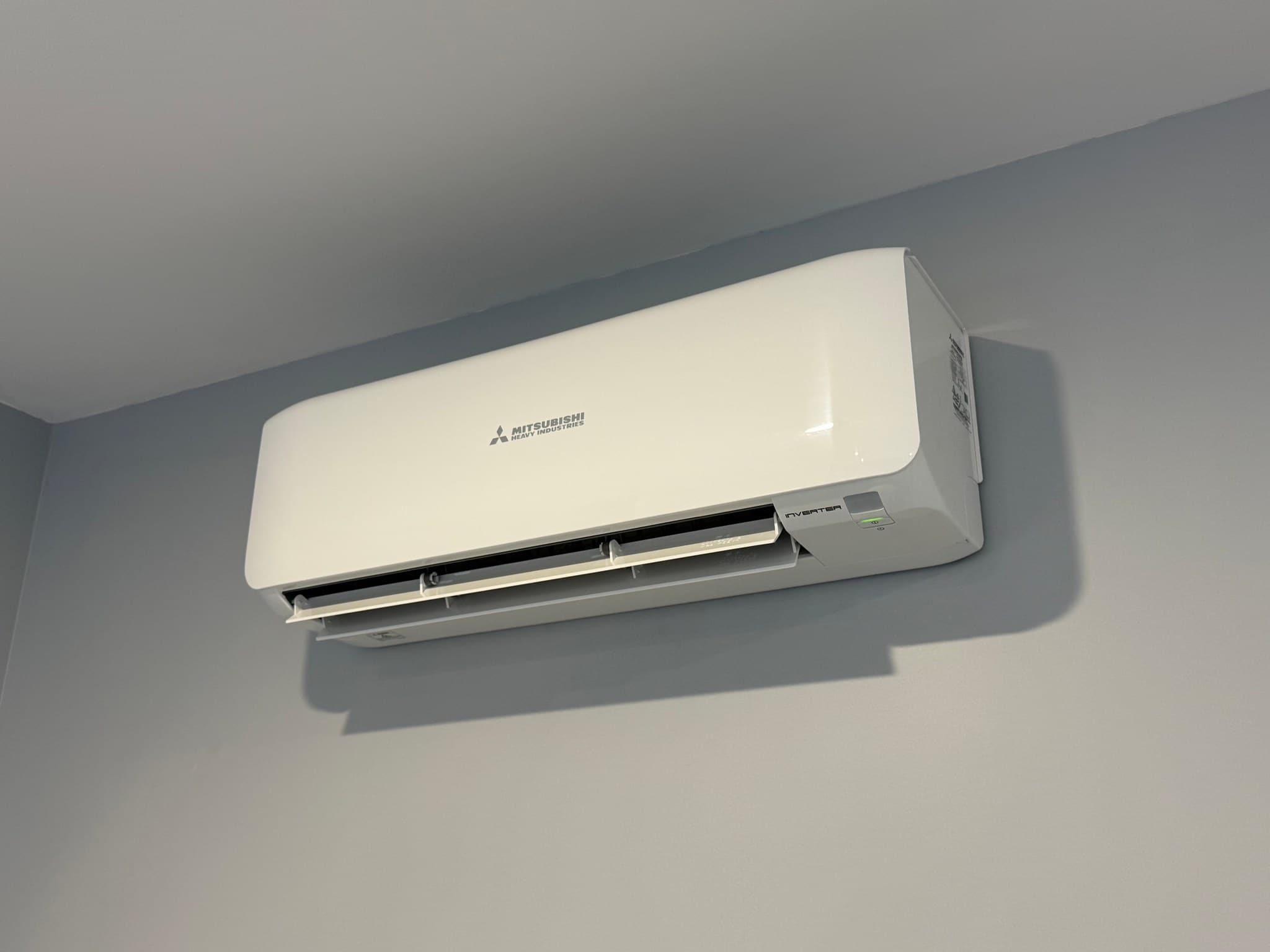 White wall-mounted split-system air conditioner with its outlet open.