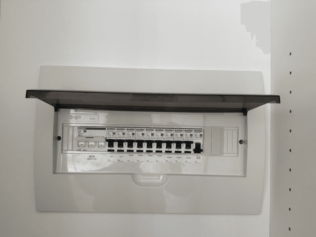 Electrical switchboard with its cover open and labelled circuit breakers.