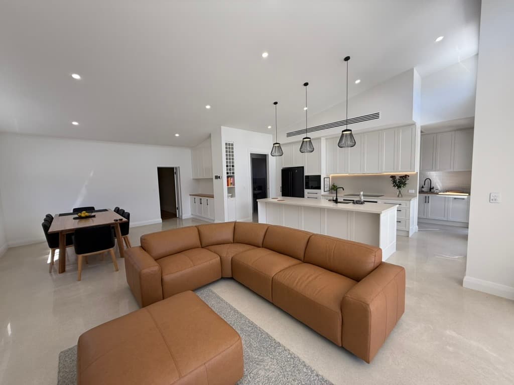 Open-plan kitchen and living room with recessed downlights, three island pendant lights and under-cabinet lighting.