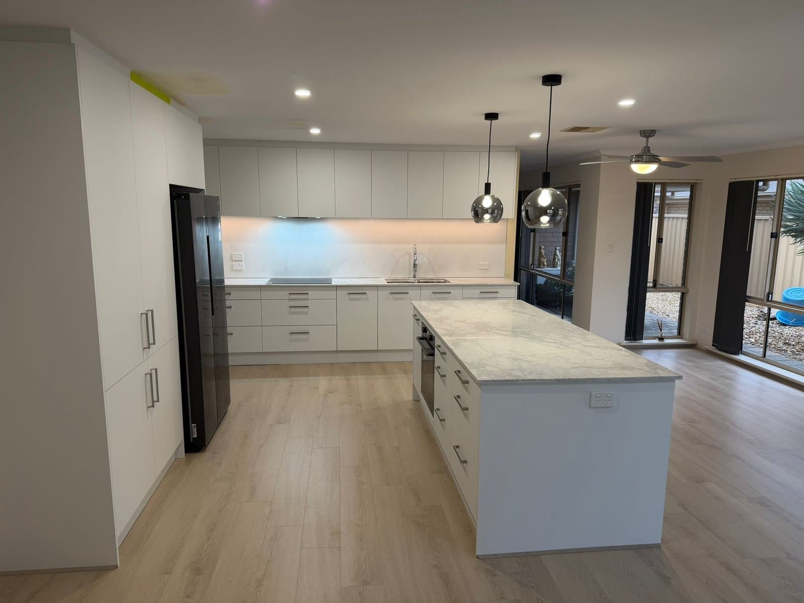 Kitchen with an island, pendant lights, downlights and illuminated splashback.